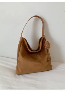 Détail du logo PANTOR embossé sur un sac cabas en daim marron avec gri-gri en peluche