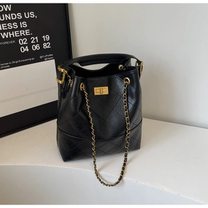 Close-up of quilted black leather texture and gold metal turn-lock on the bucket bag