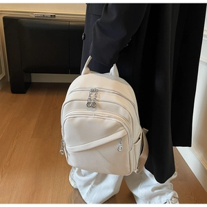 Detail of off-white lychee grain leather backpack with silver zippers and side pockets