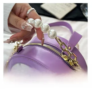 Detail of round purple crossbody bag featuring premium pearl handle and artistic print