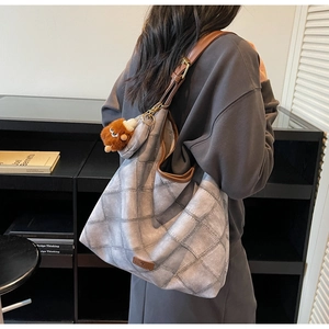 Detailed back view of a grey patchwork tote bag worn by a model with a brown plush charm