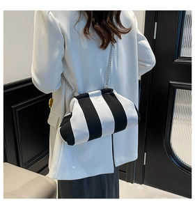 Dettaglio borsa a nuvola a righe bianche e nere con catena d'argento su blazer bianco