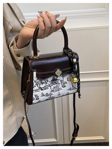 Detail of color-block handbag showing landscape print and golden floral clasp