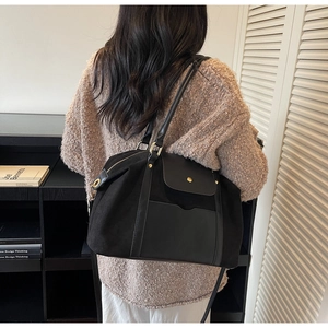 Détail d'un sac fourre-tout en cuir noir mat porté par un mannequin en intérieur