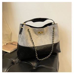 Detail of gray suede tote with black quilted leather panels and gold chain handle