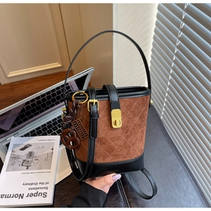 Close-up of brown quilted bucket bag with vintage metal lock next to a notebook
