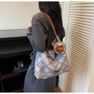 Quilted tote bag with leather strap and plush charm detail in a home interior setting