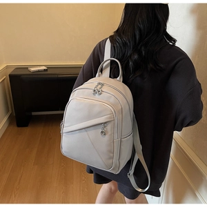 Detail of grey lychee leather backpack showing silver zippers and front pocket texture