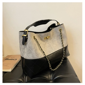 Detail of grey suede and black leather tote bag with diamond quilted stitching and gold lock