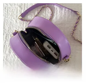Macro view of the purple round crossbody bag showing its interior capacity and gold chain