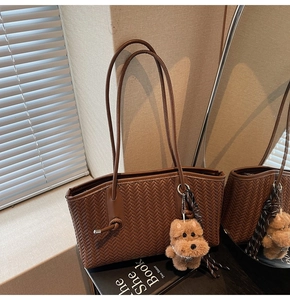 Détail du sac cabas tressé marron foncé avec pendentif chien et ruban rayé élégant