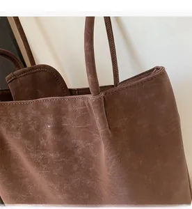 Detail view of brown vintage tote bag with textured faux leather and stitched logo