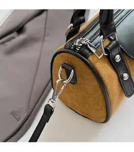 Détail de la ferrure argentée et des coutures en daim marron sur le sac polochon