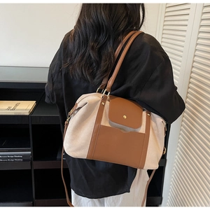 Détail du sac cabas en toile beige et cuir marron avec boucle dorée porté en bandoulière