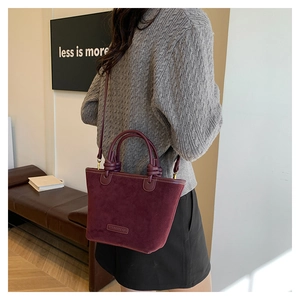Dettaglio della borsa a secchiello in camoscio bordeaux con texture e logo