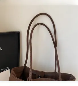 Detail of dark brown leather tote bag showing sturdy handles and fine stitching quality