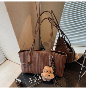 Détail du sac cabas tressé marron foncé avec texture en V et breloque peluche