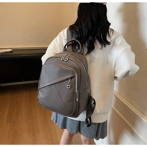 Close-up of grey pebbled leather backpack with silver ring zipper and adjustable straps