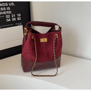 Detail of burgundy suede bucket bag featuring quilted texture and golden chain strap
