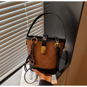 Detail of vintage quilted bucket bag with brown suede finish and metallic rotary lock