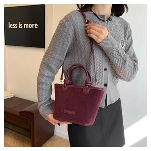 Dettaglio borsa tote in pelle scamosciata bordeaux con manico a nodo e logo inciso