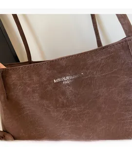 Close-up of vintage dark brown tote bag showing textured leather and brand lettering