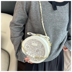 Detail of white round crossbody bag with gold chain, large pearls, and floral pattern