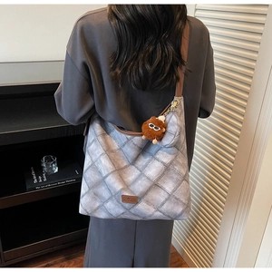 Quilted crossbody bucket bag with brown leather strap and plush monster charm