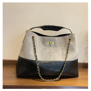 Detail of vintage suede tote bag with quilted pattern, metal chain and gold twist lock