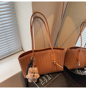 Détail d'un sac cabas marron tissé à chevrons avec breloque chiot et foulard rayé chic