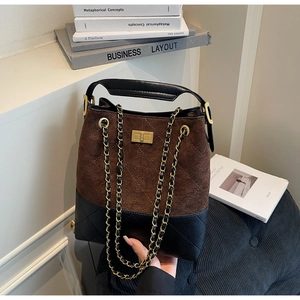 Detail of suede bucket bag with quilted stitching, gold twist lock and chain strap