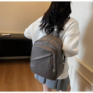 Detail of grey pebble leather backpack showing silver ring zippers and spacious pockets