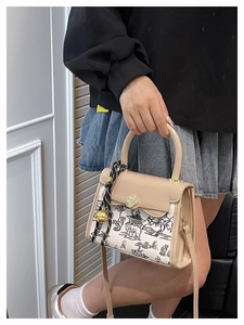 Detail of a beige canvas handbag with traditional Chinese ink painting and floral gold clasp