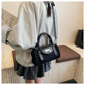 Détail du sac seau noir avec pendentif en forme de cœur et bandoulière ajustable