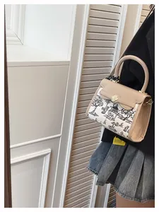 Detail view of contrast handbag featuring landscape print and floral gold lock