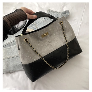 Detail of grey suede and black leather tote bag with diamond quilting and chain strap