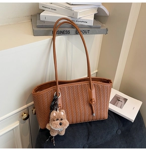 Gros plan détaillé du sac cabas tissé marron avec une breloque d'ours mignonne