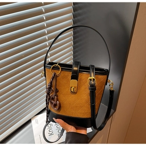 Macro view of retro quilted bucket bag featuring contrast leather trim and butterfly charm