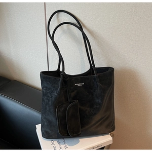 Detail of vintage black tote bag with matte texture and small matching pouch on white books