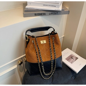 Detailed close-up of vintage brown suede and black quilted leather bucket bag with gold lock