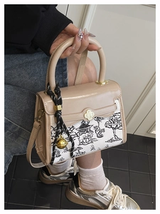 Detail of contrast color crossbody bag featuring landscape art and golden bell charm