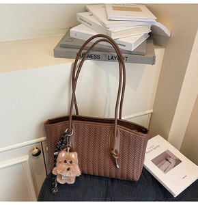 Gros plan du sac cabas tressé marron avec texture en V et breloque chiot en peluche