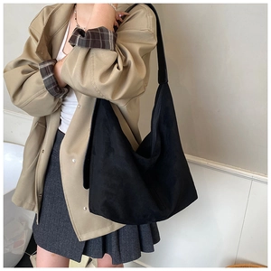 Black suede hobo shoulder bag with wide leather strap shown on model for daily commute