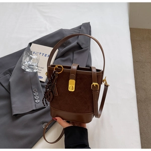 Detailed view of brown patchwork bucket bag with quilted suede and golden lock
