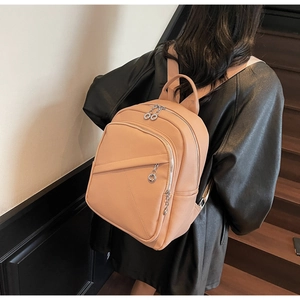 Detailed back view of a soft pink pebbled faux leather backpack with multi-zipper design