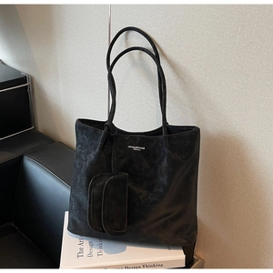 Close-up of black vintage tote bag with distressed leather texture and mini coin purse