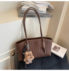 Détail d'un sac cabas marron foncé avec texture tissée en V et pendentif chien en peluche
