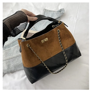 Detailed close-up of suede and quilted leather tote with golden metal twist lock and chain