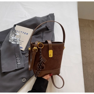 Brown suede bucket bag with quilted pattern and gold twist lock in a stylish setting