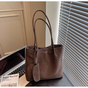 Brown leather tote bag with MUOJIN logo, mini charm pouch and modern workspace details